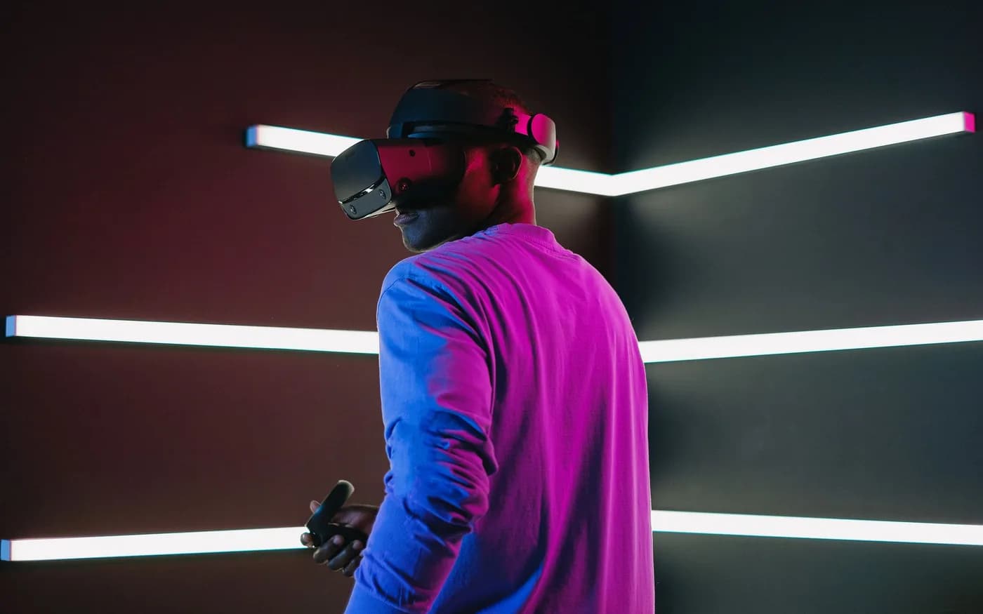 Adult wearing a virtual reality headset in a dark gaming environment